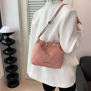Elegante rosa gesteppte Eimertasche aus Leder mit Metallkettenriemen am Model