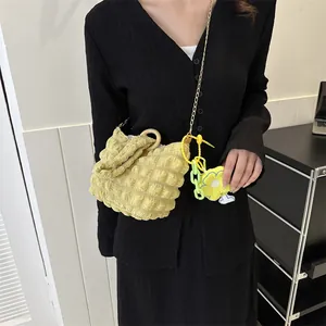 Detail of yellow quilted bubble bag with wooden handle and floral charm on a model
