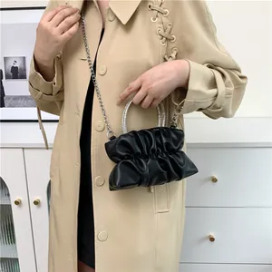 Détail d'un sac à main noir plissé avec poignée en strass et bandoulière sur mannequin