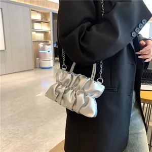Détail du sac nuage plissé argenté avec poignée en strass porté par un mannequin