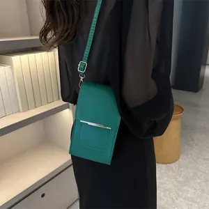 Vertical rectangular emerald green shoulder bag with leather texture and metal buckle detail
