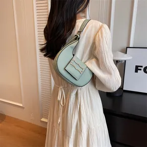 Detail of light green crescent shoulder bag with golden geometric buckle on white dress