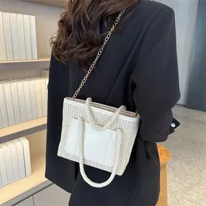 Détail du sac cabas tissé beige avec poignées en corde et bandoulière dorée