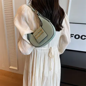 Detail of mint green crescent shoulder bag with golden buckle on white dress