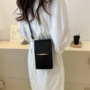 Detail of minimalist black crossbody phone bag with gold metal trim and adjustable strap