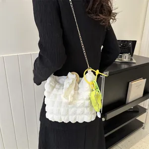 Detail of off-white bubble texture bag with gold chain strap and floral charm