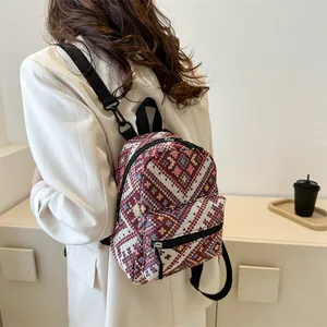 Détail d'un mini sac à dos à motif ethnique porté par un mannequin en veste blanche