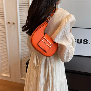 Detailed side view of orange crescent underarm bag with silver geometric buckle decoration