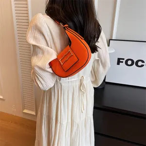 Detail of orange crescent underarm bag with gold buckle on a white dress