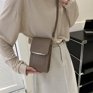 Close-up of a minimalist light brown crossbody phone bag with gold metal bar detailing