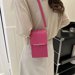 Close-up of vibrant pink leather vertical phone bag with minimalist gold metal bar