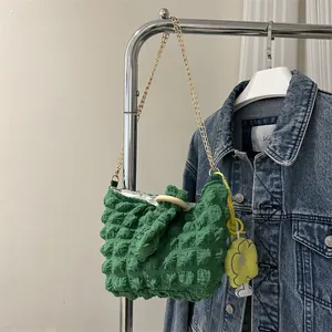 Detail of green puff bubble fabric handbag with gold chain strap and yellow flower charm