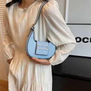 Minimalist light blue crescent shoulder bag with silver buckle worn by female model