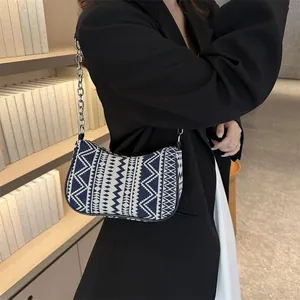 Detalle de bolso étnico con diseño geométrico y correa de cadena metálica elegante