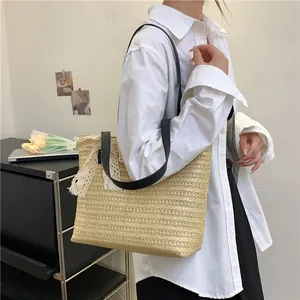 Detail of woven straw tote bag with black leather strap and white lace ribbon bow