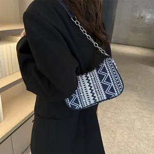 Detalle de bordado étnico azul y blanco con correa de cadena plateada en el bolso