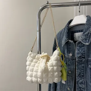 Detail of white bubble texture fabric bag with gold chain strap and neon charm