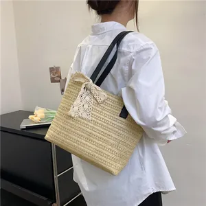 Detail of woven straw tote bag with large lace bow and black leather shoulder strap