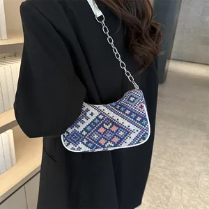 Detalle de bolso hobo tejido con patrones geométricos y correa de cadena plateada
