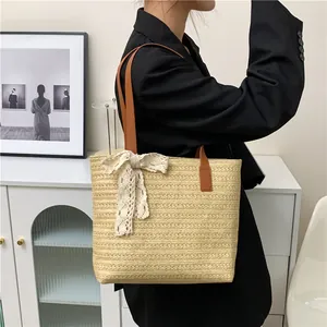Large beige woven straw tote bag with white lace bow and leather straps on model