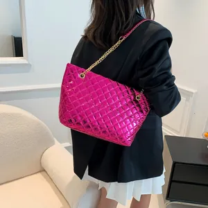 Quilted tote bag in fuchsia metallic finish with gold chain strap shown on shoulder