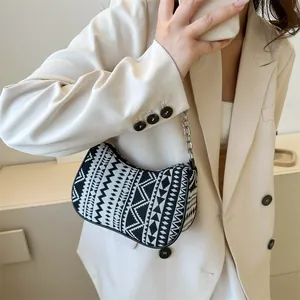 Detalle del bolso de hombro tejido con patrón geométrico y cadena de metal plateado