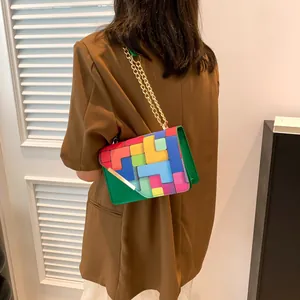 Detail view of colorful geometric patchwork chain bag with golden V-shaped metal clasp