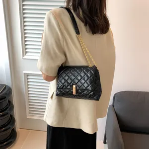 Close-up of black quilted leather shoulder bag with golden metal chain and clasp