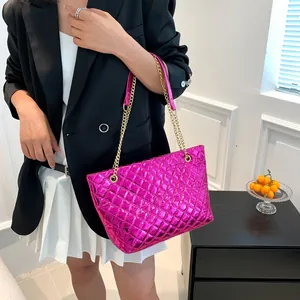 Detail of hot pink quilted tote bag with gold chain strap on a professional model