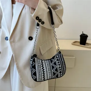 Detalle de bolso de hombro pequeño con patrón étnico geométrico y correa de cadena metal