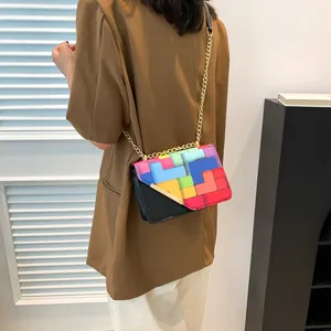 Detail view of a colorful geometric patchwork crossbody bag with a gold chain strap