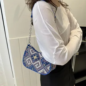 Detalle del bolso de hombro azul con estampado jacquard geométrico y cadena de plata