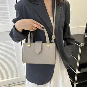Detail of grey lychee leather handbag with gold metal hardware and crossbody strap