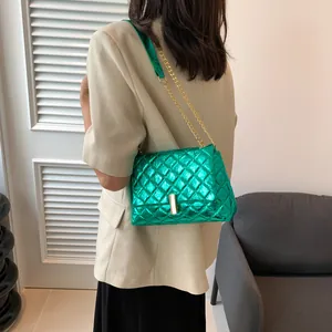 Close-up of metallic green quilted crossbody bag with gold chain strap on a model