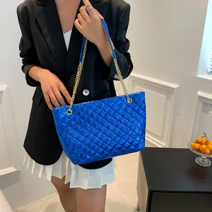 Close-up of quilted metallic blue tote bag featuring golden chain and leather strap