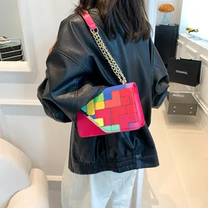 Detail of colorful geometric patchwork shoulder bag with golden chain and vibrant leather texture