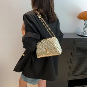 Model showcasing a quilted gold chain bag with metallic finish and rectangular twist lock