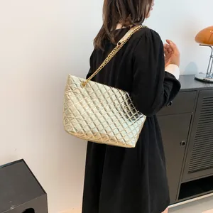 Chic quilted gold tote bag with chain strap shown on model in a modern interior setting