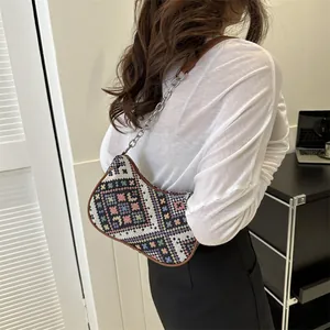 Detalle de la tela con patrón geométrico étnico y correa de cadena metálica del bolso