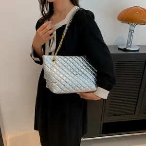 Detail of silver quilted tote bag featuring metallic finish and gold chain strap on shoulder