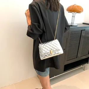 Close-up of silver quilted crossbody bag with gold chain strap worn on black blazer