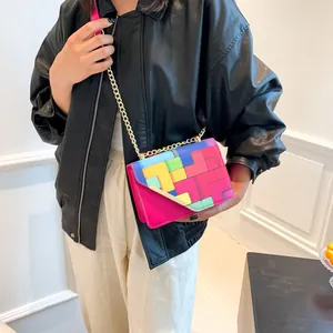Pink crossbody bag with colorful geometric patchwork and a gold chain strap