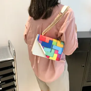Detail of colorful geometric patchwork crossbody bag with gold chain and leather strap