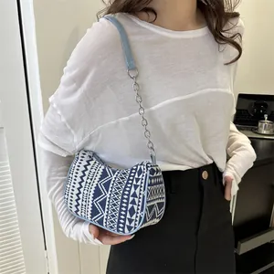 Detalle del patrón tejido étnico y correa de cuero azul con cadena plateada en el bolso