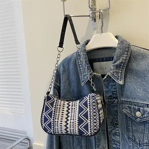 Detalle del tejido geométrico bohemio azul y blanco en un bolso de hombro con cadena