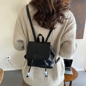 Dettaglio di mini zaino nero con patta magnetica e coulisse con perline decorative