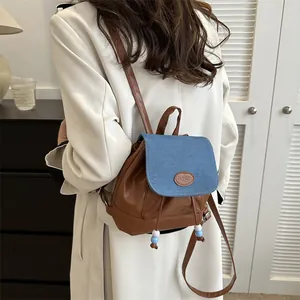 Dettaglio dello zaino a contrasto in pelle PU marrone e patta in denim blu con coulisse