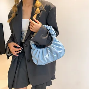 Detail of light blue pleated cloud bag styled with a grey blazer for a modern look