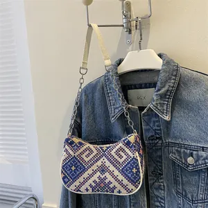 Detalle del bolso bohemio tejido con patrones geométricos y correa de cadena y cuero