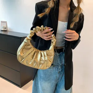 Detail of metallic gold pleated cloud bag with scrunchie handle and shiny texture